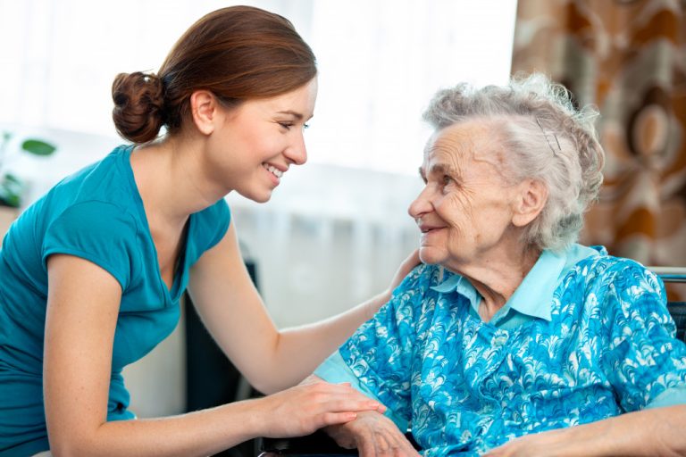 A woman smiling to an elderly woman at home