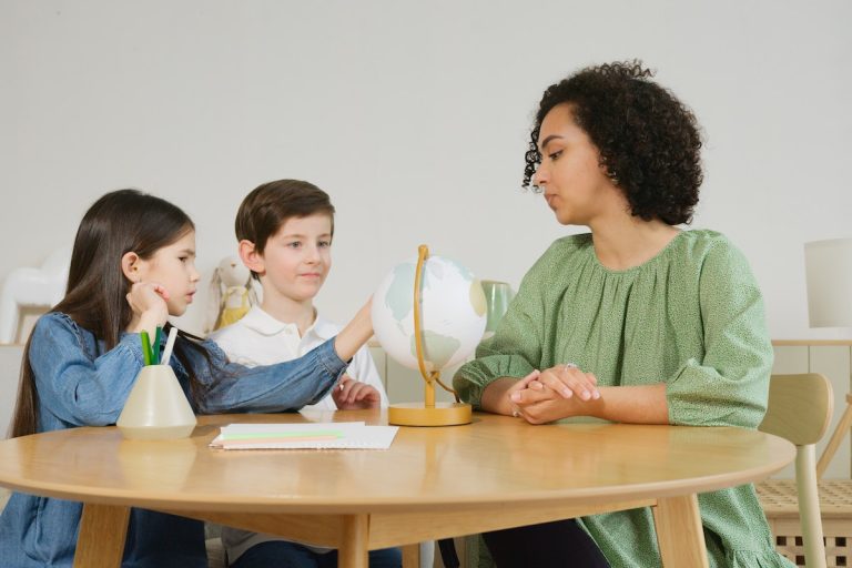 a teacher teaching two young students about the globe
