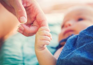 a newborn holding a parent's finger