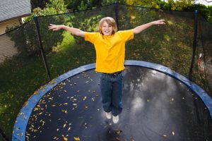A kid is jumping on a trampoline.