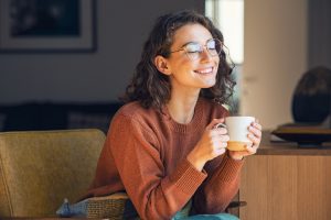 Young woman smiling while drinking tea at home.