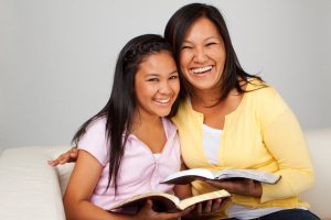 mother and daughter smiling while holding a book