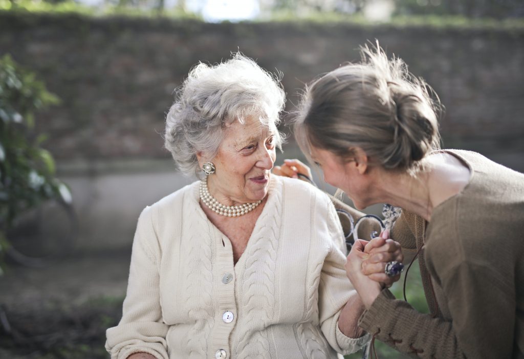 Old woman in wheelchair talking with her caregiver